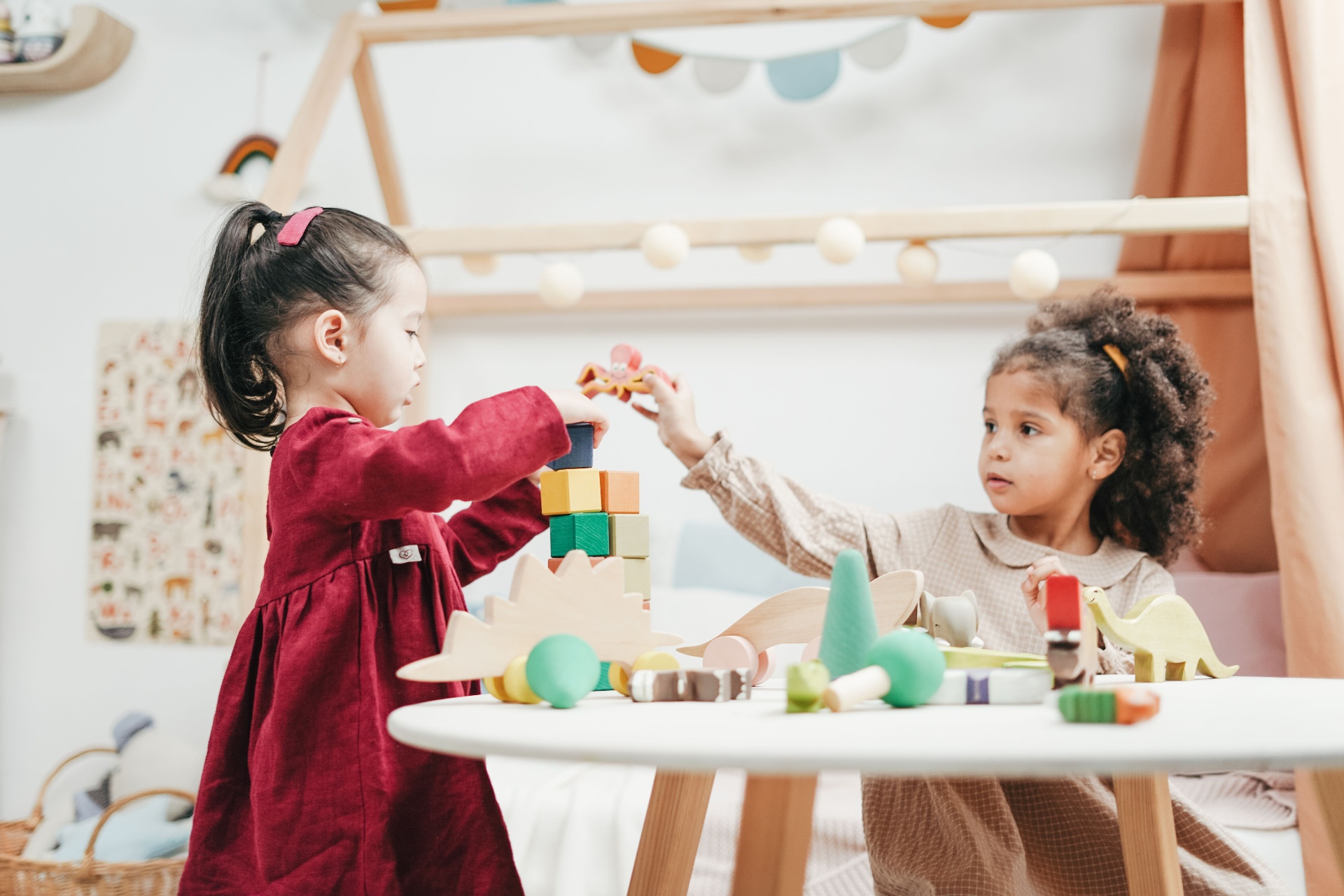 Two young children playing with wooden blocks together at a daycare table